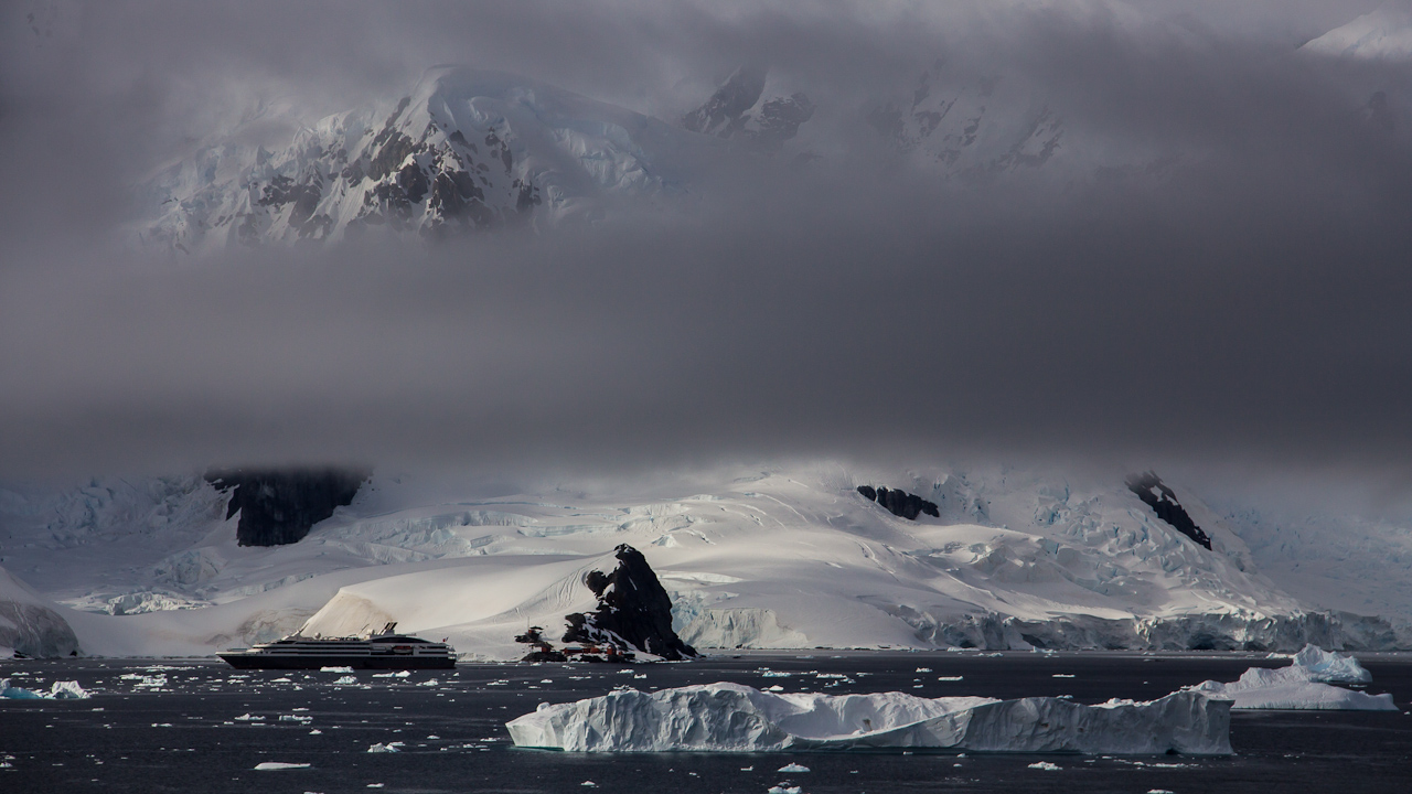 An expedition cruise ship among icebergs and mountains in Paradise Bay, Antarctica